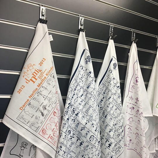 School fundraising tea towels hanging on pegs.